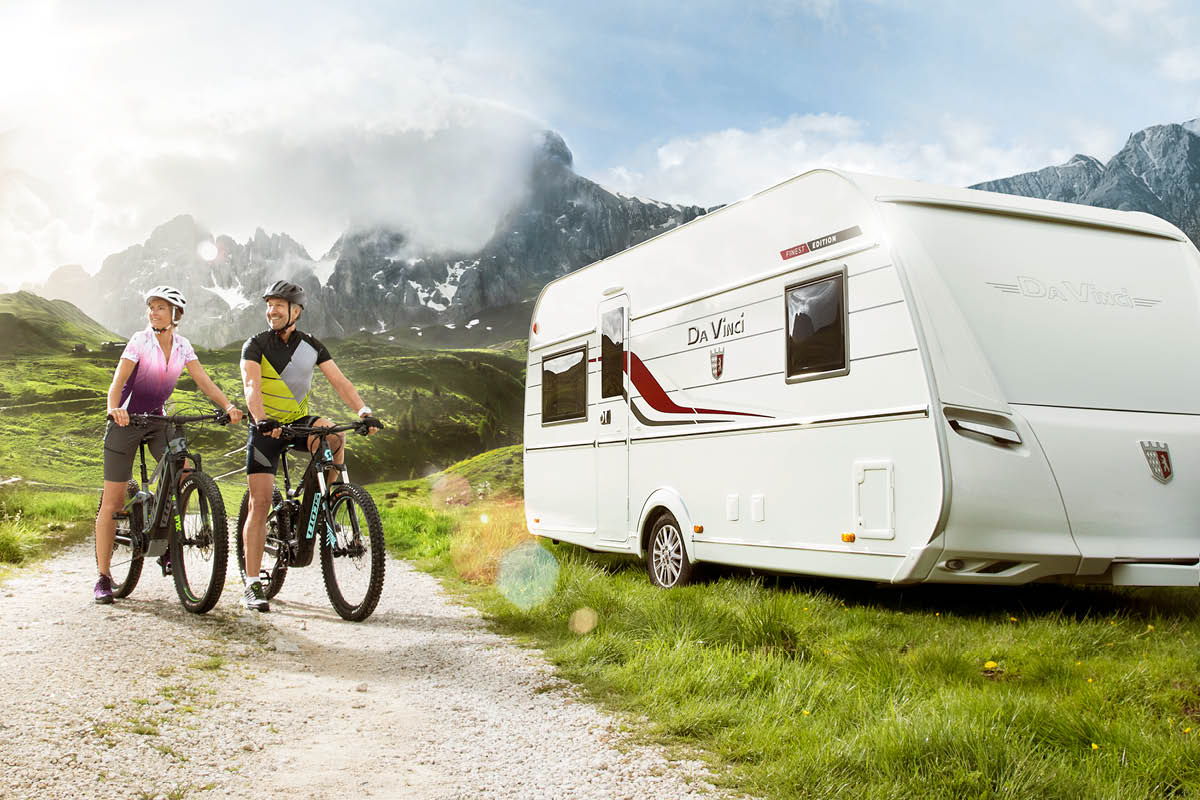 Wohnwagen in Landschaft mit Fahrradfahrern